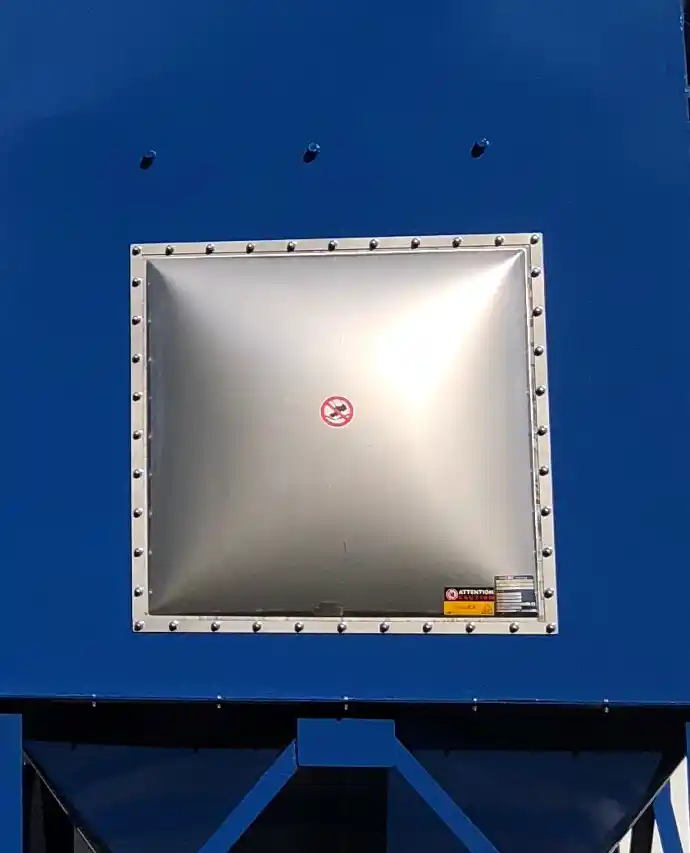 Close-up of an industrial explosion vent panel installed on a blue dust collection system, featuring a square stainless steel cover with bolted edges for pressure relief.