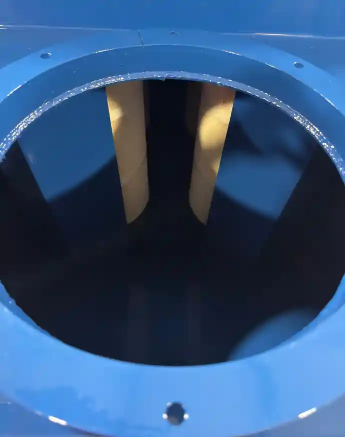 Industrial air filtration unit with deflector plates in front of cartridge filters inside a blue housing for enhanced airflow and dust collection efficiency.
