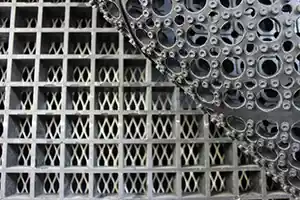 Close-up of grated industrial work surface with layered metal grid and perforated structure, providing durability and stability for industrial applications.