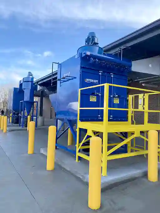 Large outdoor ProVent Intercept industrial dust collection units with yellow service platforms, safety railings, and connected ductwork, installed for efficient dust and particle filtration at an industrial facility.