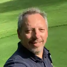 Outdoor selfie of Jim, a man with short gray hair, smiling while standing on a green lawn.